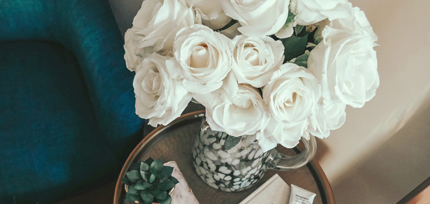 Elegant white roses in a glass vase, paired with succulents on a decorative tray.