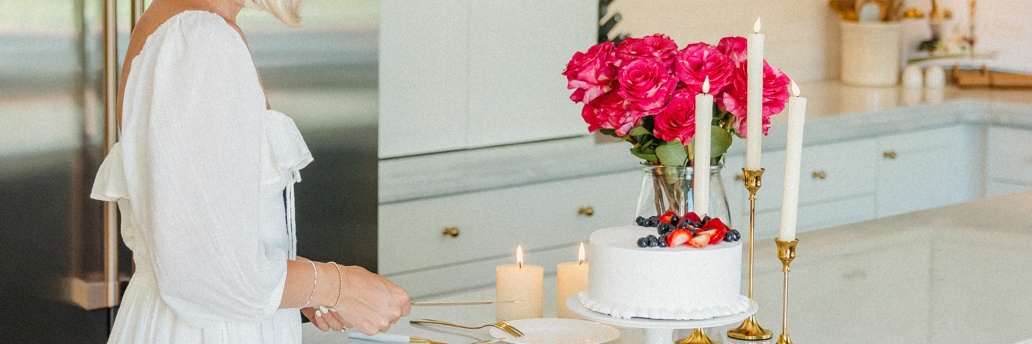 A stylish kitchen setting featuring a birthday cake and vibrant pink roses.