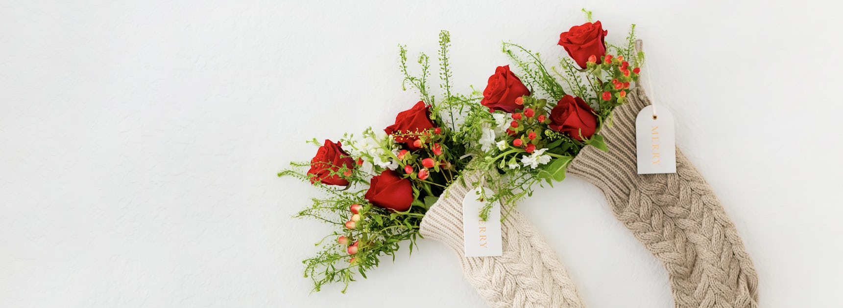 Festive Christmas stockings filled with vibrant red roses and greenery for the holidays.