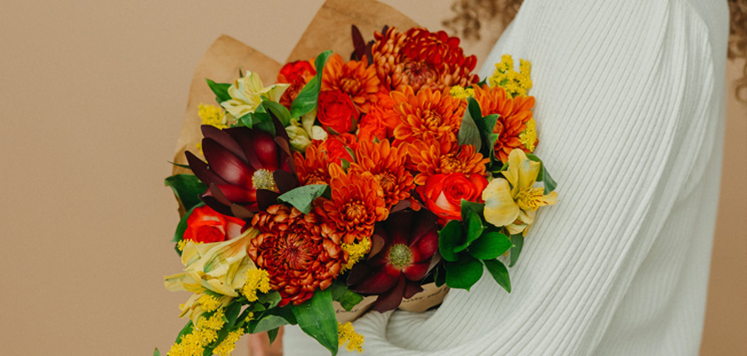 Vibrant bouquet of orange and yellow blooms, wrapped in kraft paper, perfect for autumn.