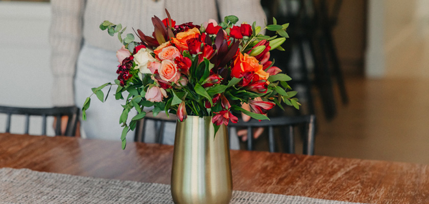 Vibrant mixed floral bouquet featuring red, orange, and pink flowers in a chic vase.