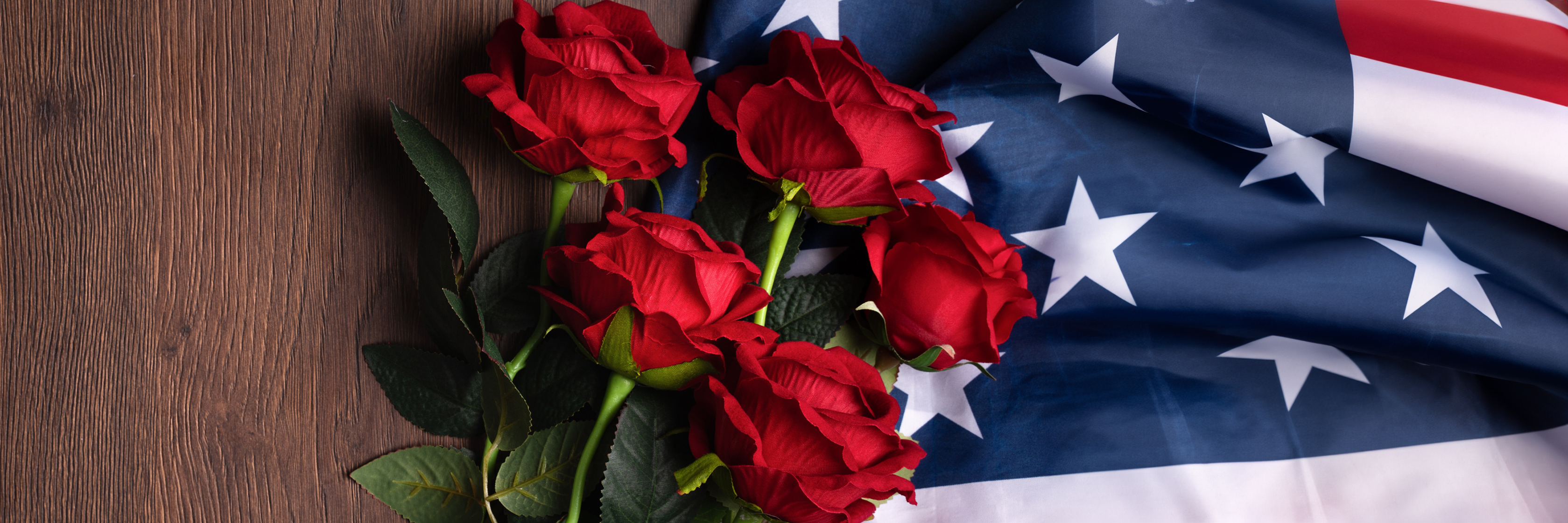 Red roses nestled against an American flag, symbolizing patriotism and love in a striking display.