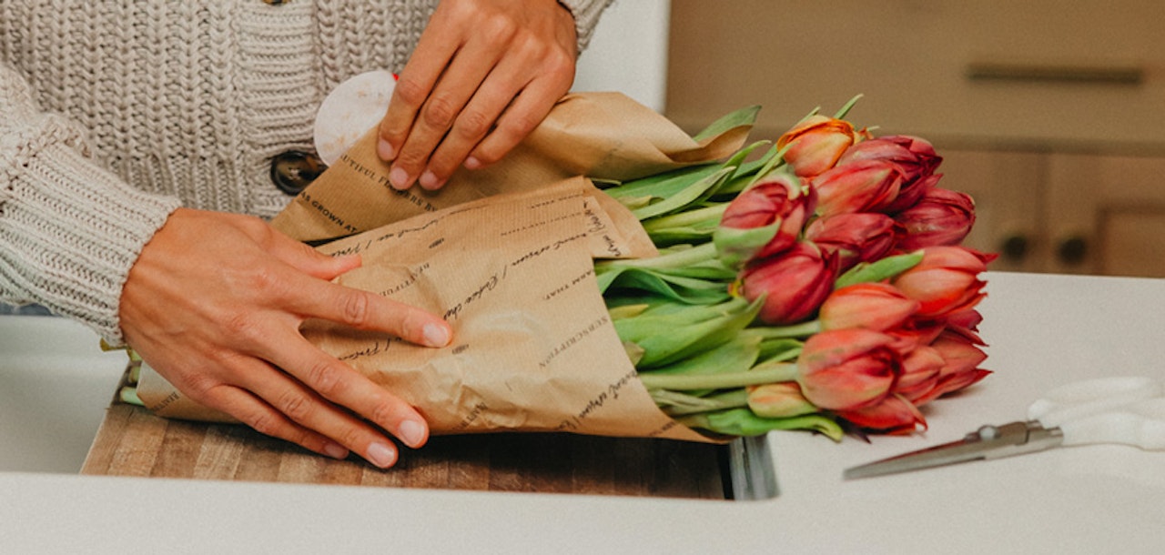 Beautifully wrapped bouquet of vibrant tulips being prepared for a special occasion.