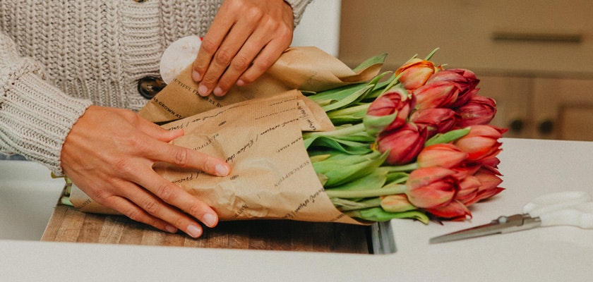 Beautifully wrapped bouquet of vibrant tulips being prepared for a special occasion.