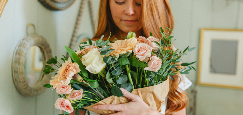 A cheerful woman holding a charming bouquet of pastel flowers, radiating warmth and joy.