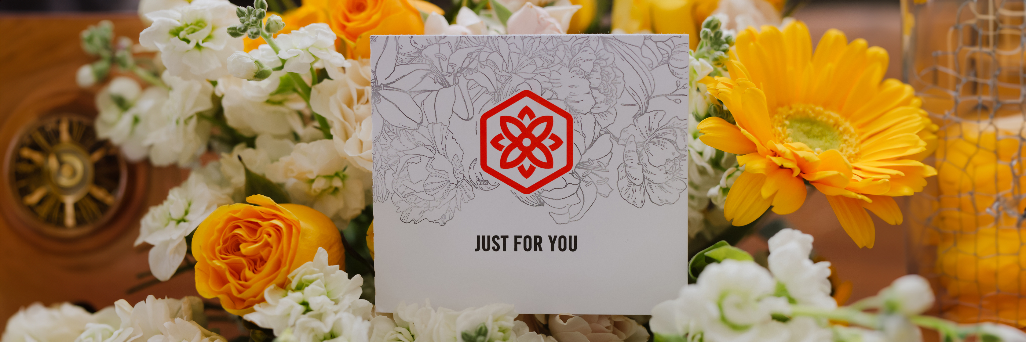 Bright and cheerful flower arrangement featuring yellow gerberas, roses, and a special note card.