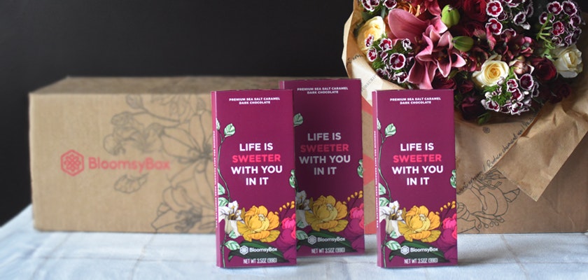 Beautiful floral arrangement in a BloomsyBox package, surrounded by elegant gift cards.