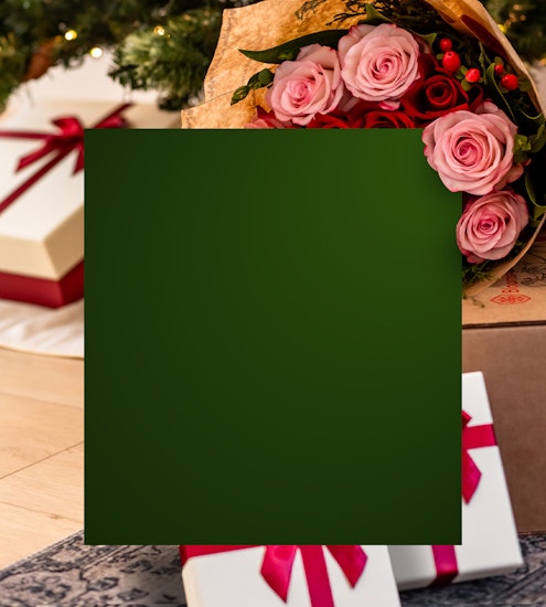 Beautiful holiday bouquet of pink and red roses surrounded by festive gift boxes and lush greenery.