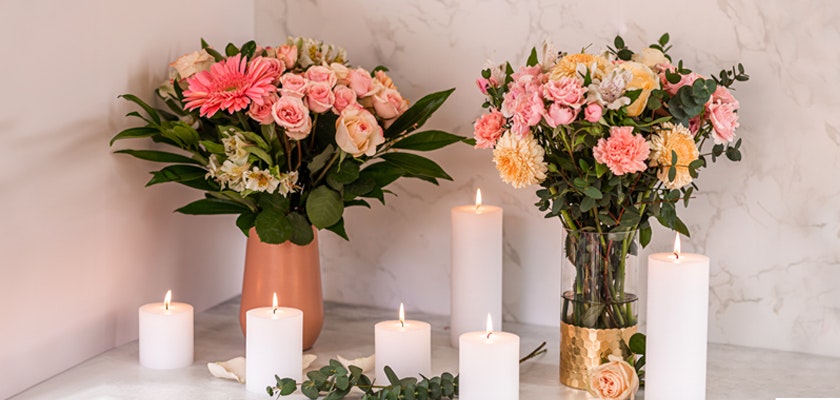 Two elegant floral arrangements featuring pink and peach blooms, complemented by lit candles.