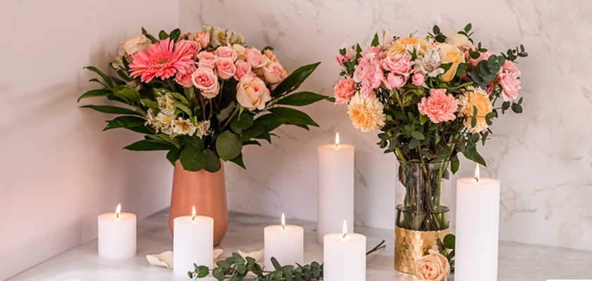 Two elegant floral arrangements featuring pink and peach blooms, complemented by lit candles.