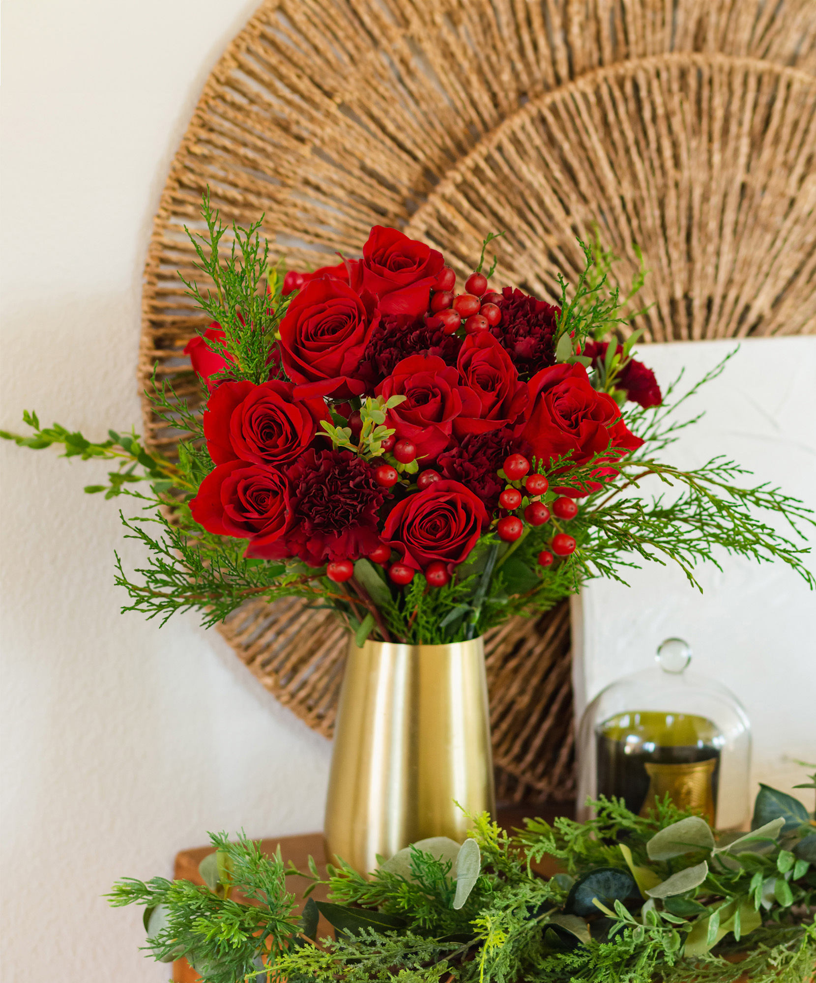 Vibrant red roses and greenery arranged in a stylish gold vase, perfect for home decor.