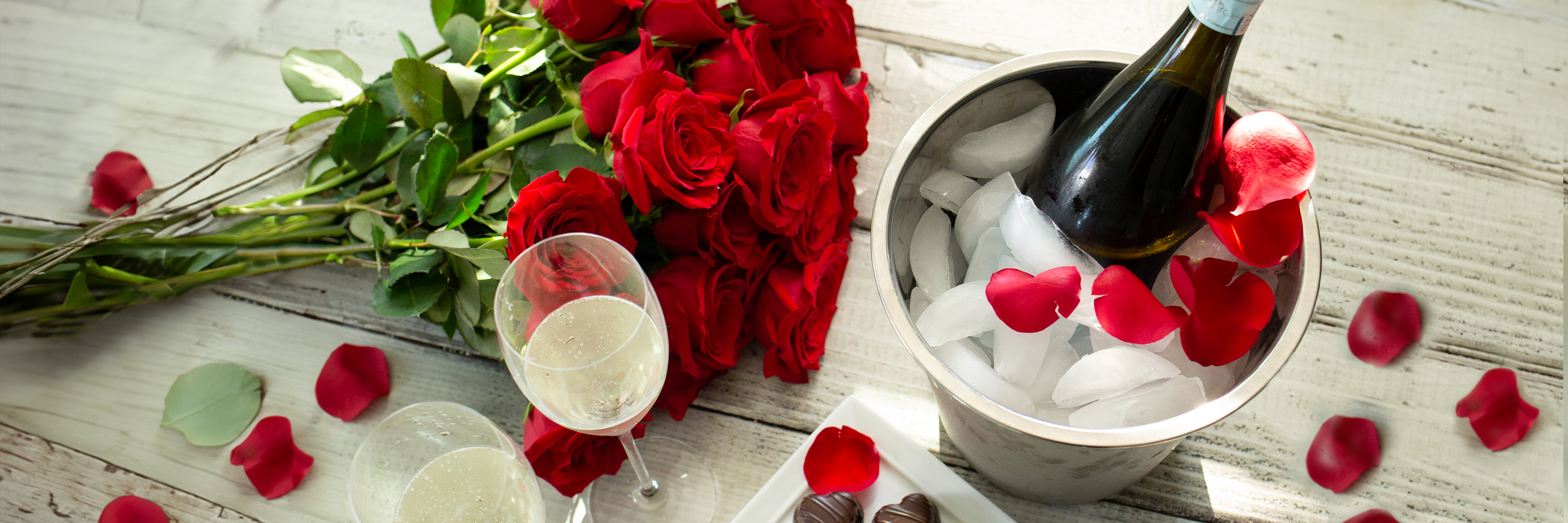 Elegant red roses beside champagne in an ice bucket, perfect for romantic celebrations.