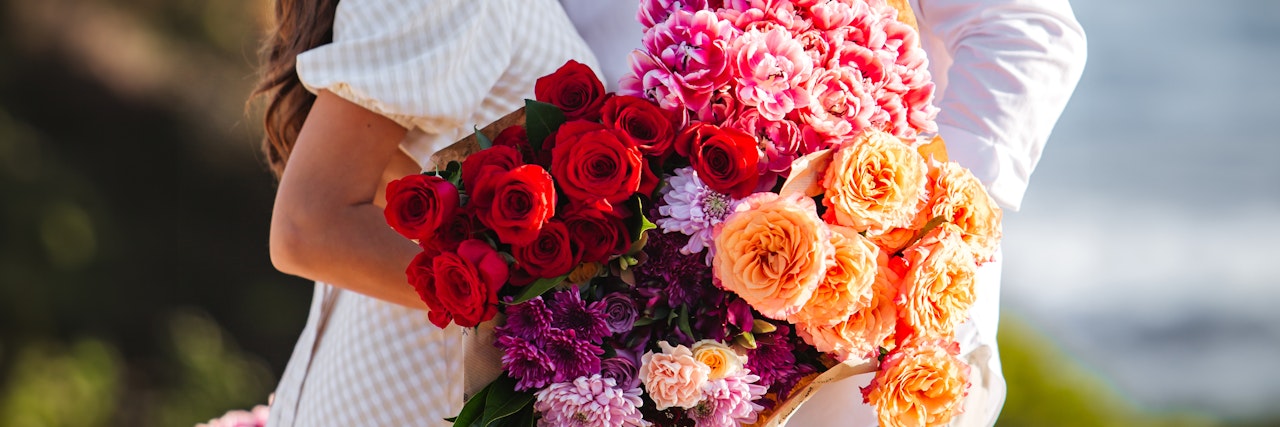 A vibrant floral arrangement featuring red, pink, and orange roses, perfect for romantic occasions.