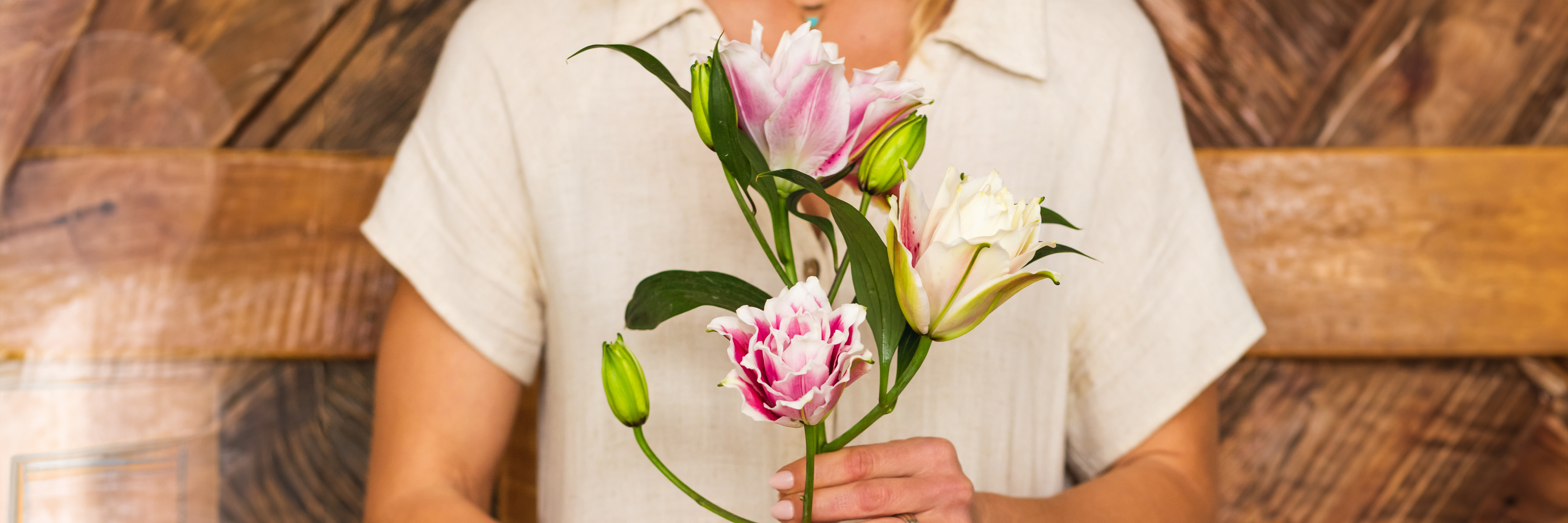 Delicate pink and white tulips held by a woman in a rustic setting, ideal for spring celebrations.