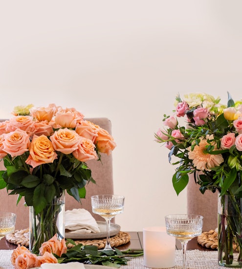 Beautiful peach roses and pastel blooms in elegant arrangements for a chic dining table setting.