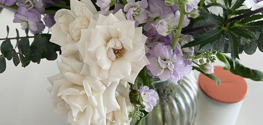 Elegant white roses and soft purple blooms in a chic glass vase, ideal for home decor or gifting.