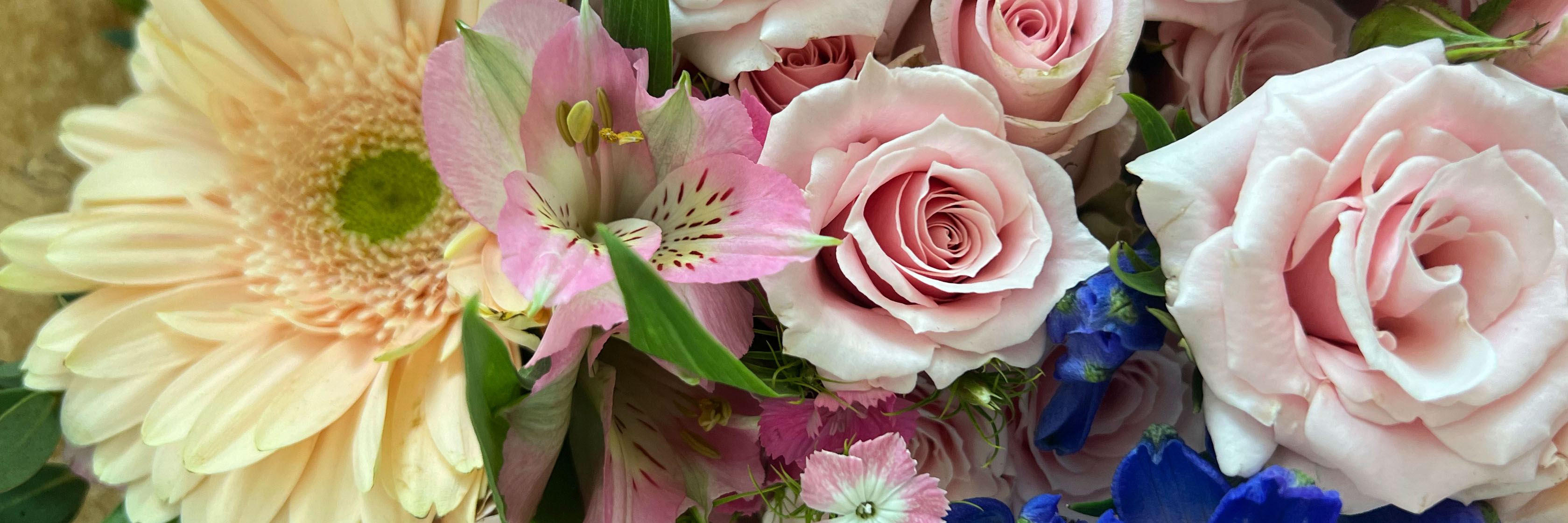 A delightful bouquet featuring soft pink roses, vibrant daisies, and colorful blooms.