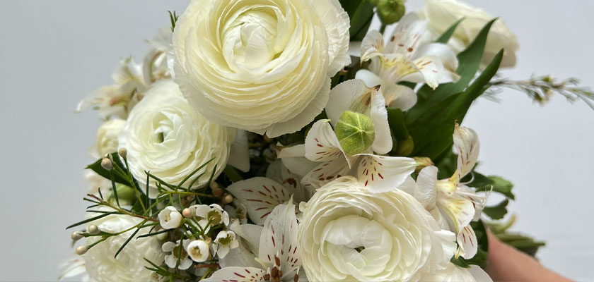 Elegant white floral bouquet featuring ranunculus and delicate blooms, perfect for weddings.