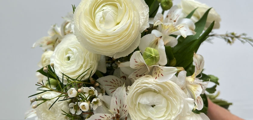 Elegant white floral bouquet featuring ranunculus and delicate blooms, perfect for weddings.