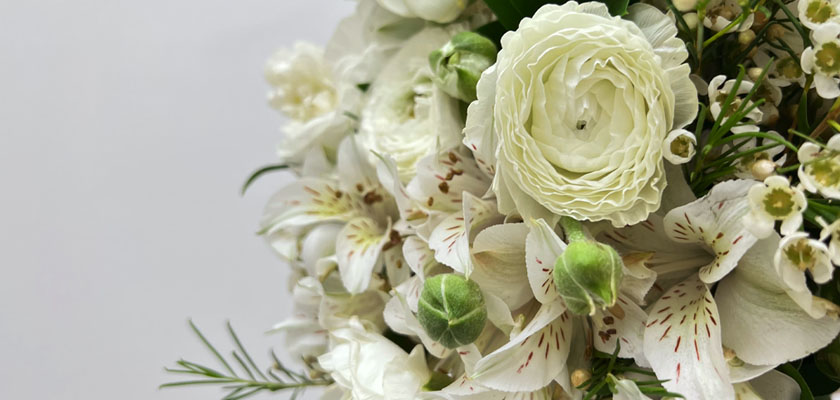 Elegant white floral arrangement featuring ranunculus, alstroemeria, and delicate greenery.