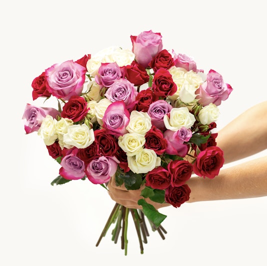 Elegant bouquet of purple, hot pink, and white roses in a lush floral arrangement.