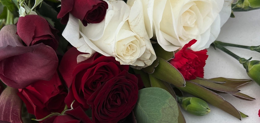 Elegant floral arrangement featuring white and deep red roses, accented with green foliage.