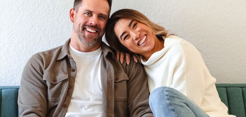 Happy couple smiling together on a cozy sofa, radiating joy and warmth in a casual setting.