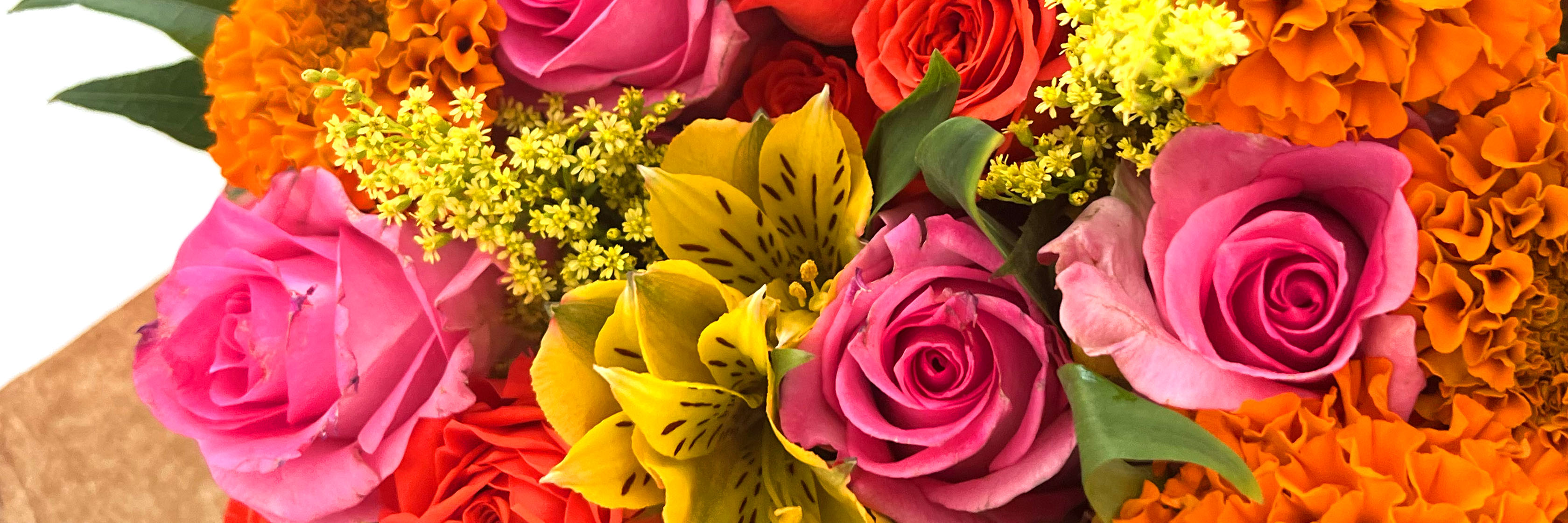 Vibrant floral arrangement featuring pink roses, yellow alstroemeria, and marigolds.