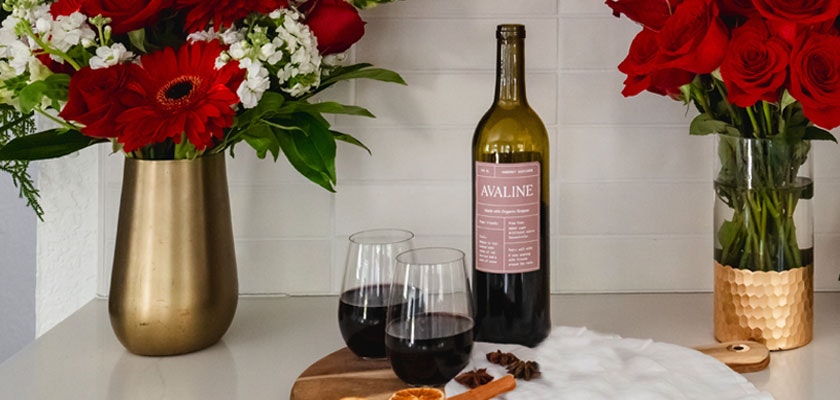 Elegant wine pairing setup featuring red roses and vibrant gerbera daisies with glasses.