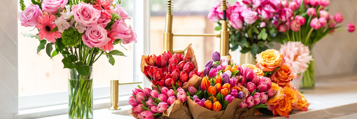 Vibrant floral display featuring pink roses and colorful tulips in a sunlit setting.