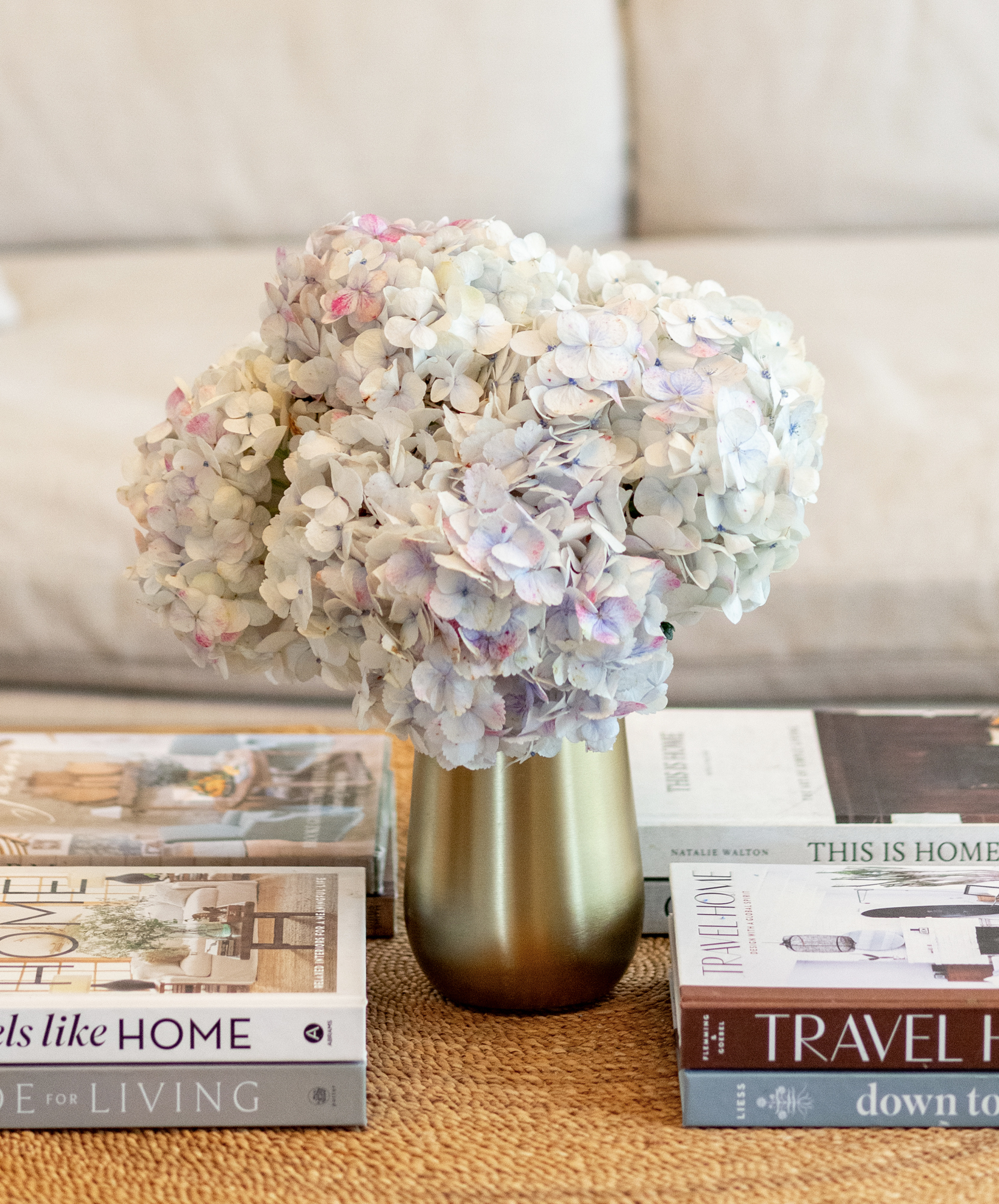 A delicate bouquet of soft-hued hydrangeas in a gold vase, accentuating a cozy living space.