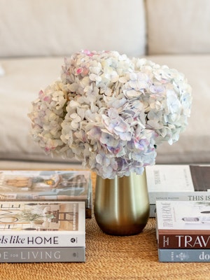 A delicate bouquet of soft-hued hydrangeas in a gold vase, accentuating a cozy living space.