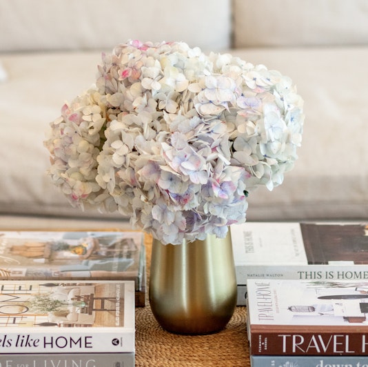 A delicate bouquet of soft-hued hydrangeas in a gold vase, accentuating a cozy living space.