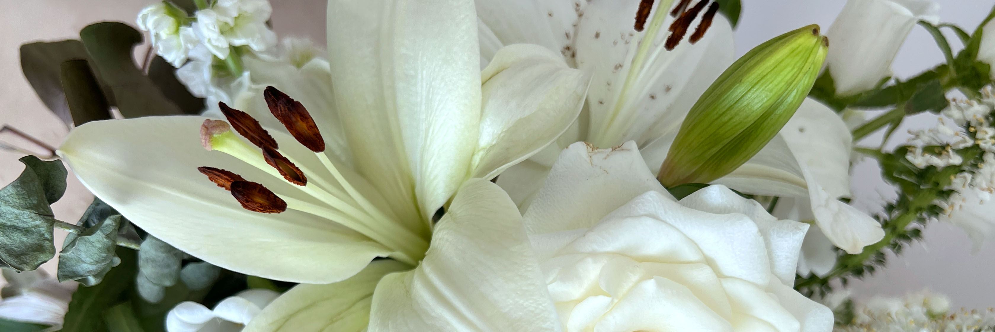 Elegant white lilies and roses paired with lush greenery in a stunning floral arrangement.