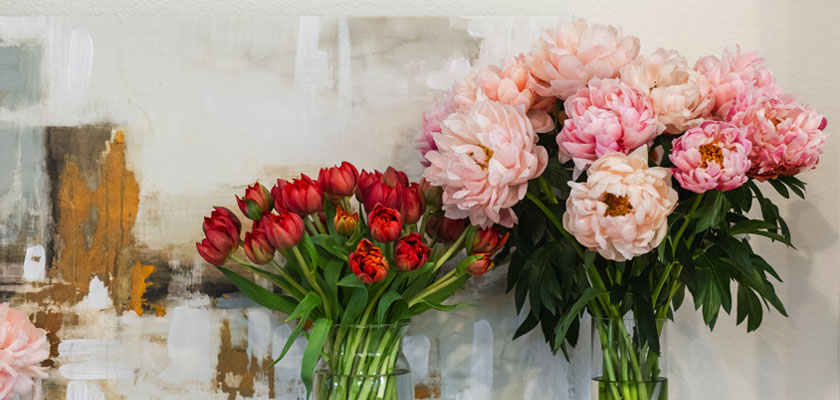 Vibrant floral arrangement featuring red tulips and soft pink peonies in elegant vases.