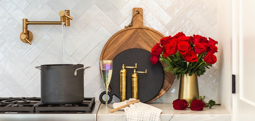 Elegant kitchen scene featuring a striking bouquet of red roses beside a chic pot and modern decor.