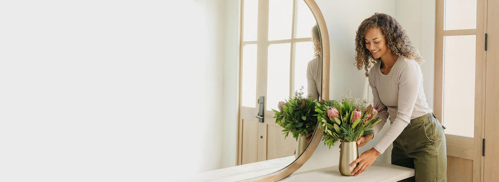 A woman arranges a fresh flower bouquet in a sleek vase, enhancing her modern decor.