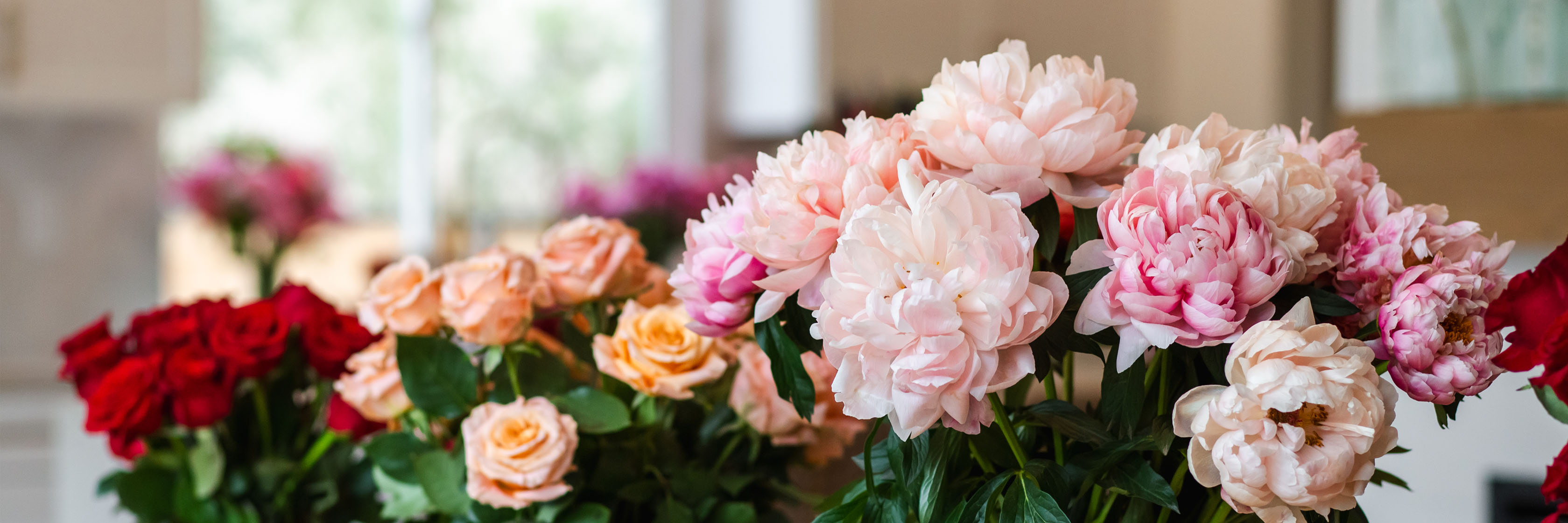 Vibrant floral display featuring red roses and pink peonies in a beautifully arranged bouquet.