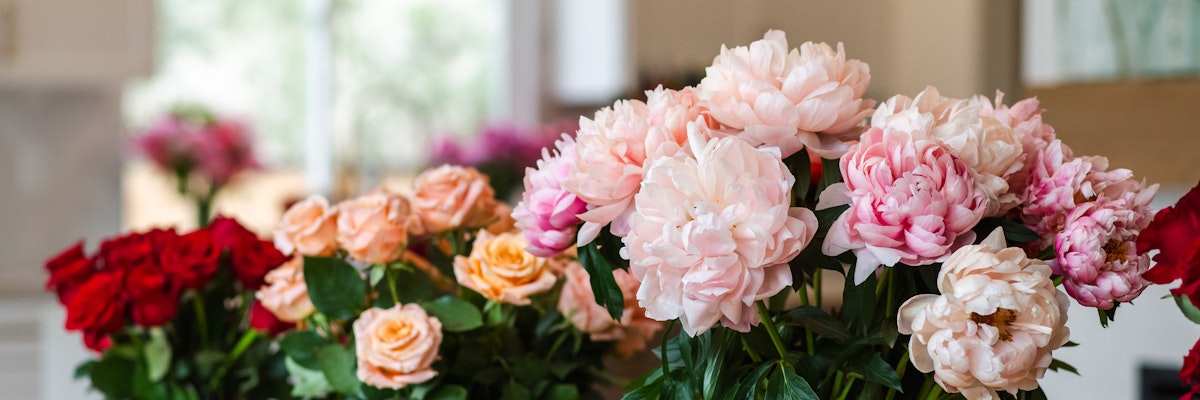 Vibrant floral display featuring red roses and pink peonies in a beautifully arranged bouquet.