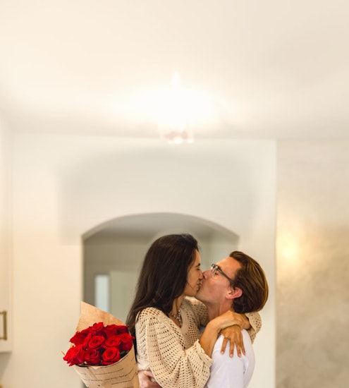 A couple joyfully embracing amidst a beautiful bouquet of red roses, radiating love and happiness.