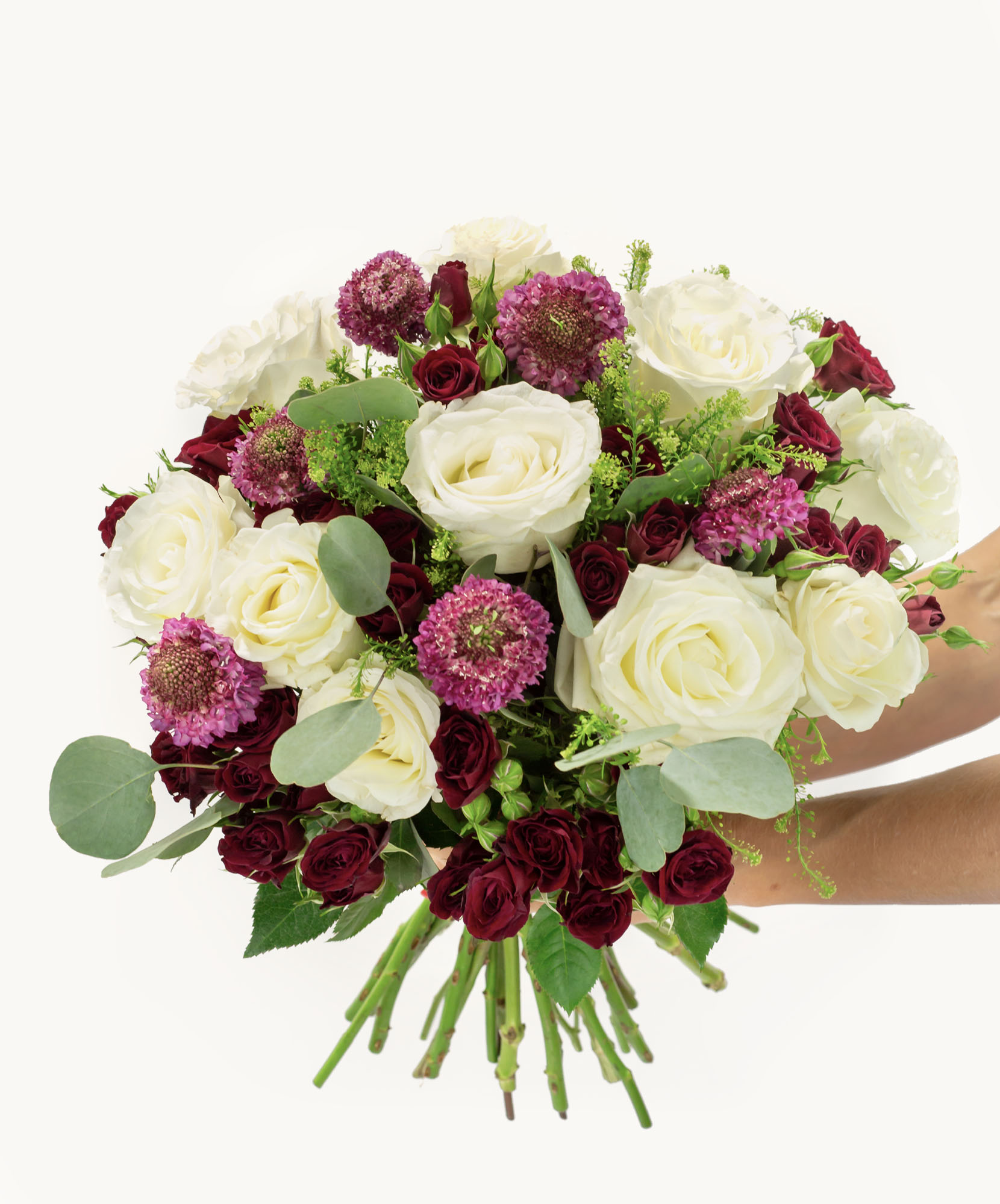 A vibrant bouquet featuring white and deep red roses with lush greenery and purple accents.