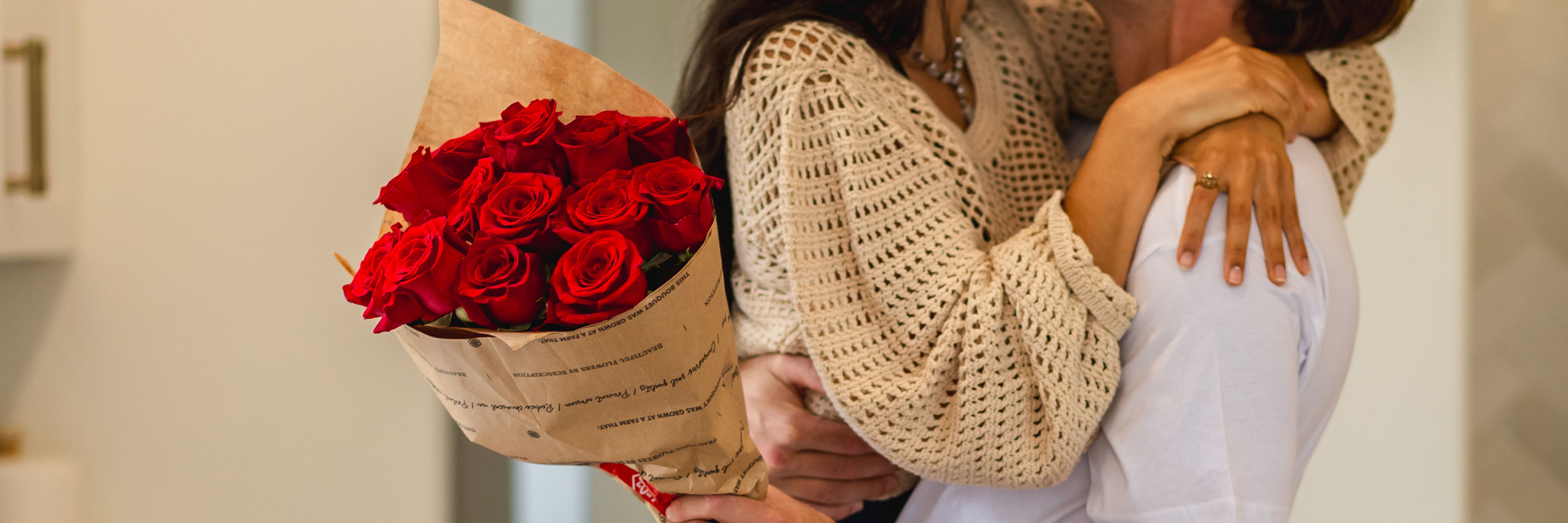 A joyful couple embraces, featuring a vibrant bouquet of red roses, symbolizing love.