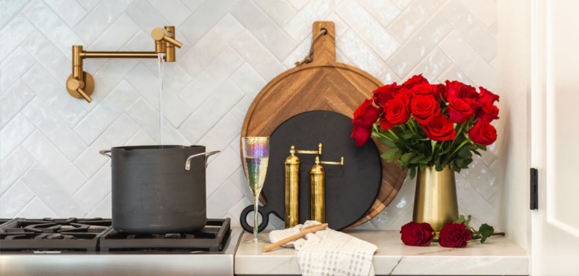 Elegant kitchen scene featuring a pot, gold accents, and a vibrant red rose bouquet.