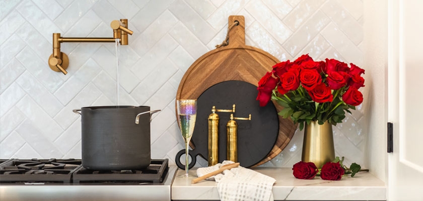 Elegant kitchen scene featuring a pot, gold accents, and a vibrant red rose bouquet.