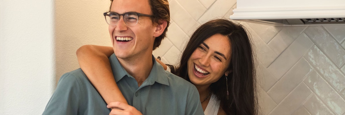 A joyful couple laughing together in a cozy kitchen, sharing a heartfelt moment.