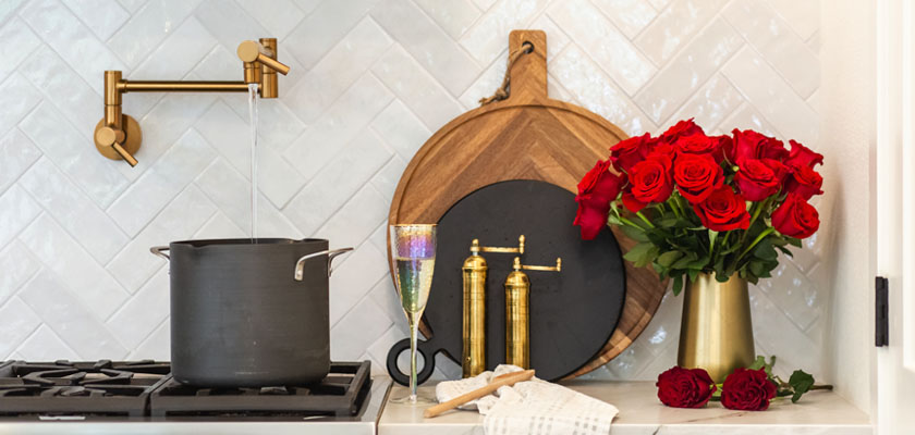 A stylish kitchen scene featuring a pot on the stove and a vibrant bouquet of red roses.