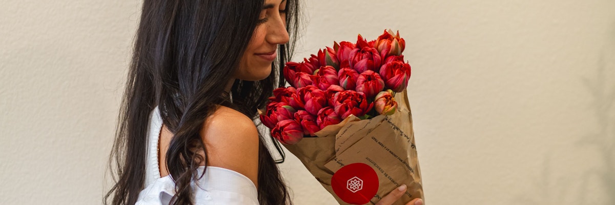 A woman holds a stunning bouquet of vibrant red tulips, radiating joy and elegance.