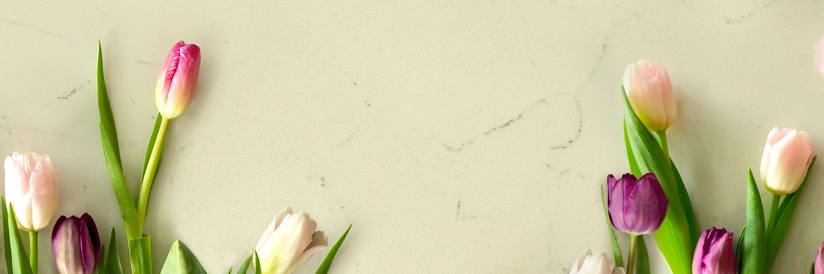 A vibrant arrangement of pink and purple tulips on a light marble surface, perfect for spring decor.