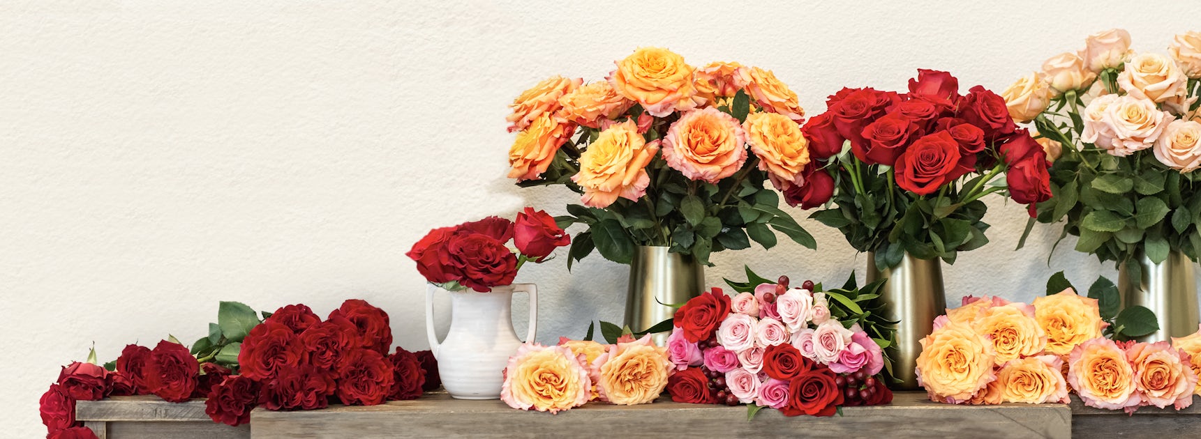 Vibrant display of colorful roses in various shades, elegantly arranged on a rustic wooden table.