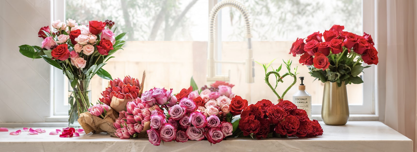 A vibrant display of assorted roses in various colors, arranged beautifully on a bright windowsill.